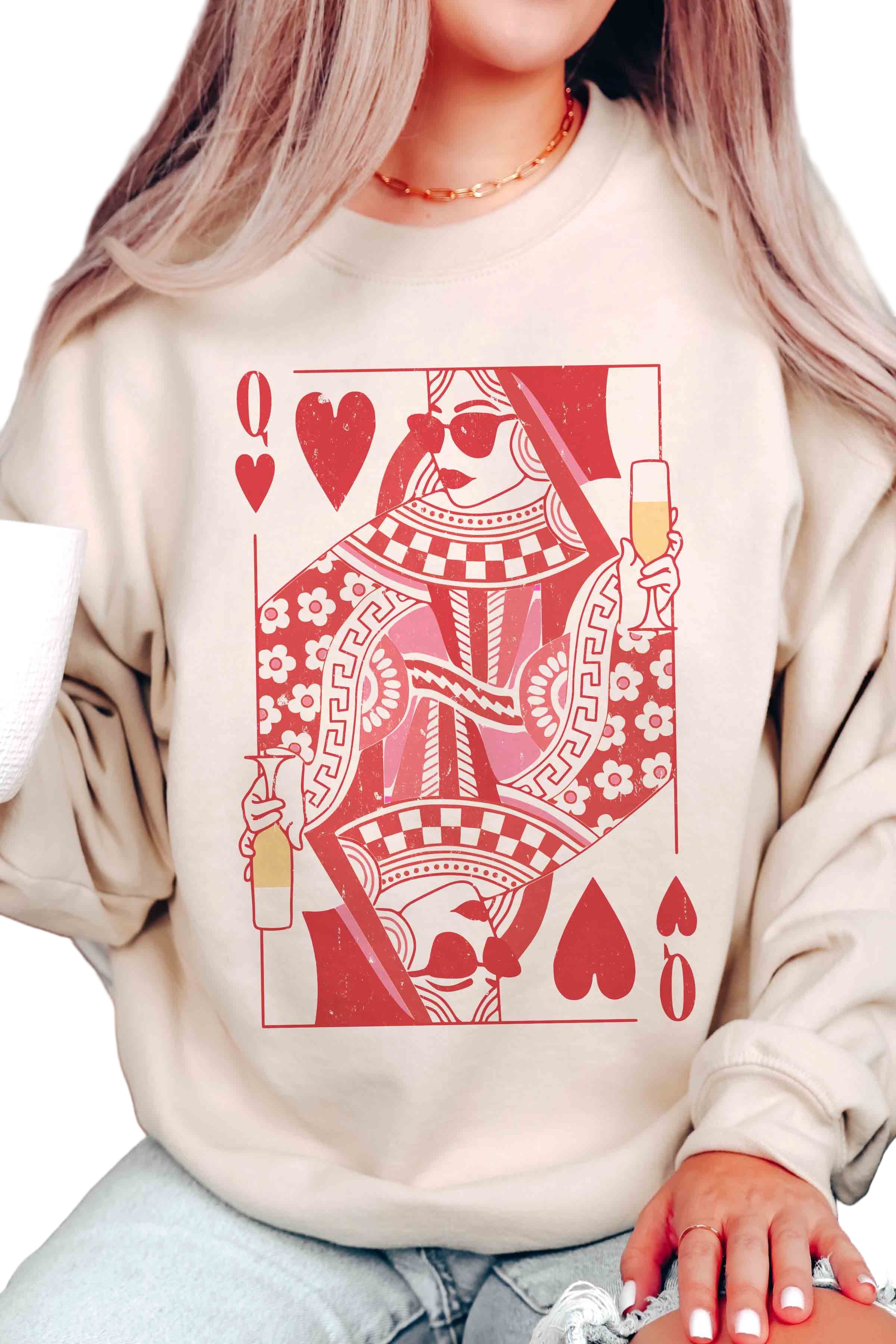 Person wearing a cream sweatshirt with a red and white graphic design of a queen of hearts playing card.