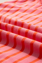 Close-up of JUNIPER BLVD striped drop shoulder sweatshirt in pink and orange fabric folds