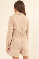 Back view of a beige corduroy romper for vacation with an elastic waist and long sleeves