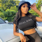 Woman wearing aesthetic streetwear summer top with real bad print and black bucket hat outdoors