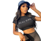 Woman wearing aesthetic streetwear summer top with Real Bad print in black and a black cap outdoors