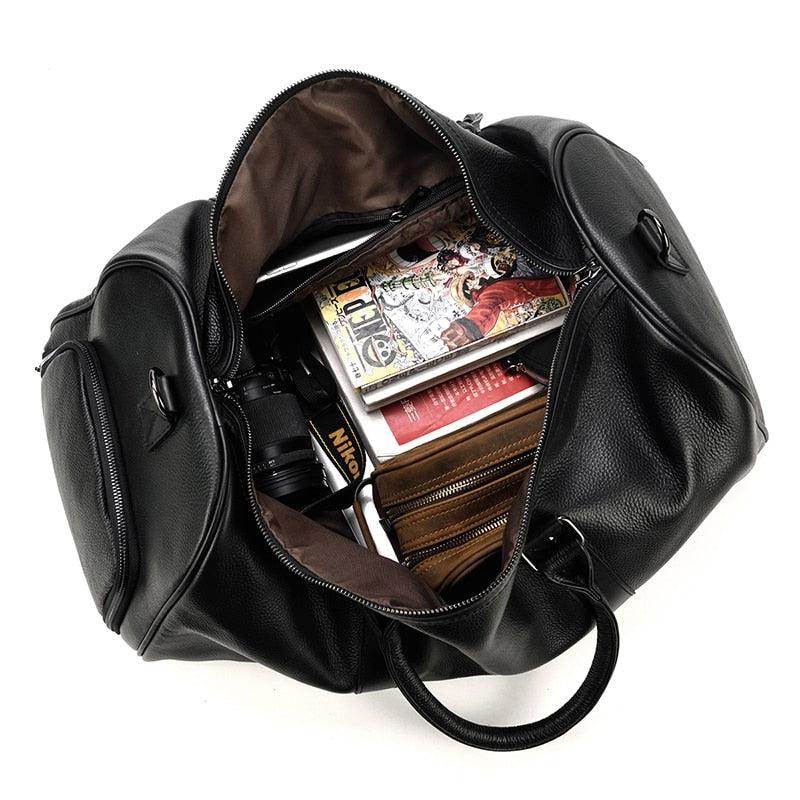 Spacious black leather weekend bag opened with various items inside including books and a camera