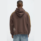 Back view of man wearing brown graphic hoodie for men with yellow stripes on sleeves by VacationGrabs