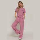 Woman wearing pink casual vacation lounge pants with matching t-shirt outfit by VacationGrabs