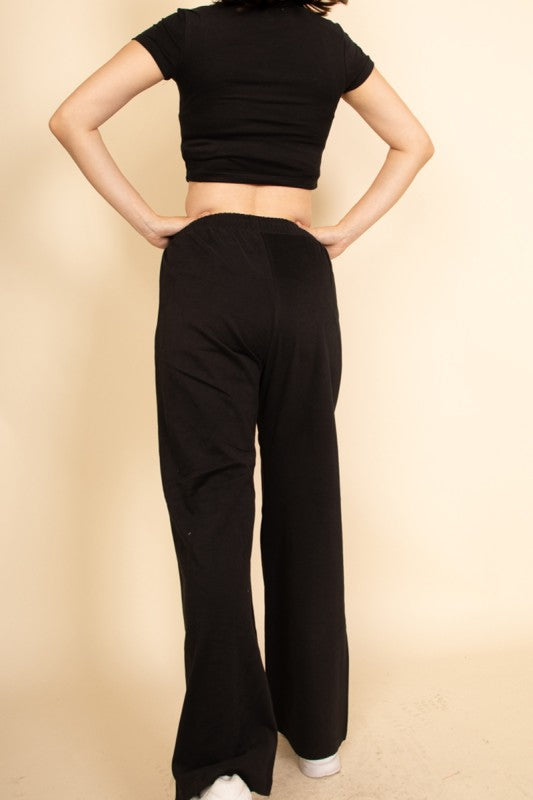 Casual wide-leg pants outfit by Capella featuring black relaxed high-waisted pants and a fitted black crop top