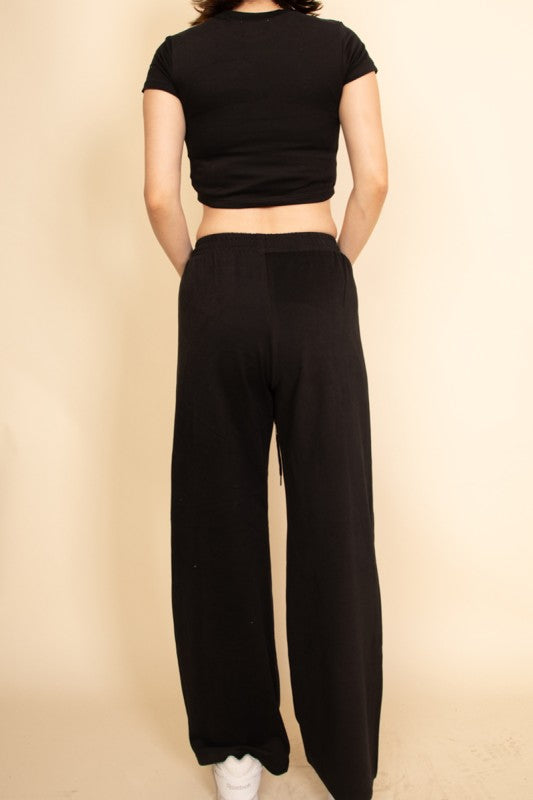Back view of casual wide-leg pants outfit in black worn with black cropped top and white sneakers
