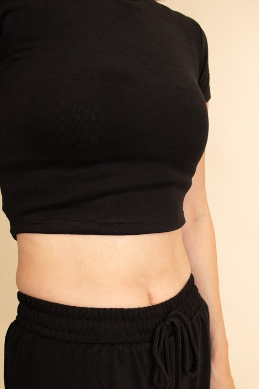 Close-up of a casual wide-leg pants outfit featuring black drawstring pants and a black crop top