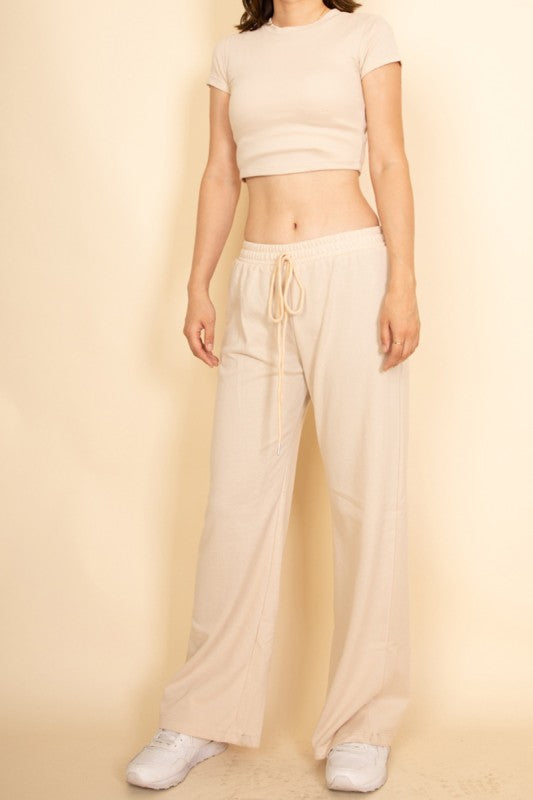 Woman wearing Capella beige casual wide-leg pants outfit with a cropped top and white sneakers