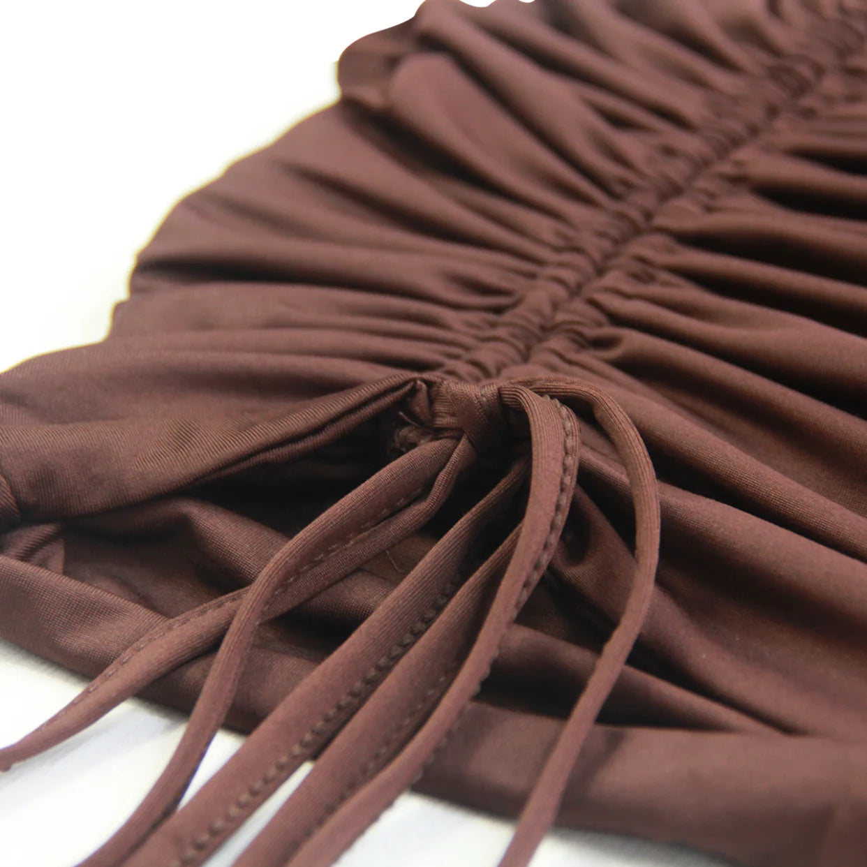 Close-up of brown fabric detail with ruched design and ties on a sexy spaghetti strap mini dress