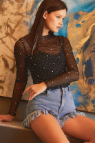 YNIQUE black rhinestone mesh top sheer long sleeve mock neck with rhinestones paired with frayed denim shorts