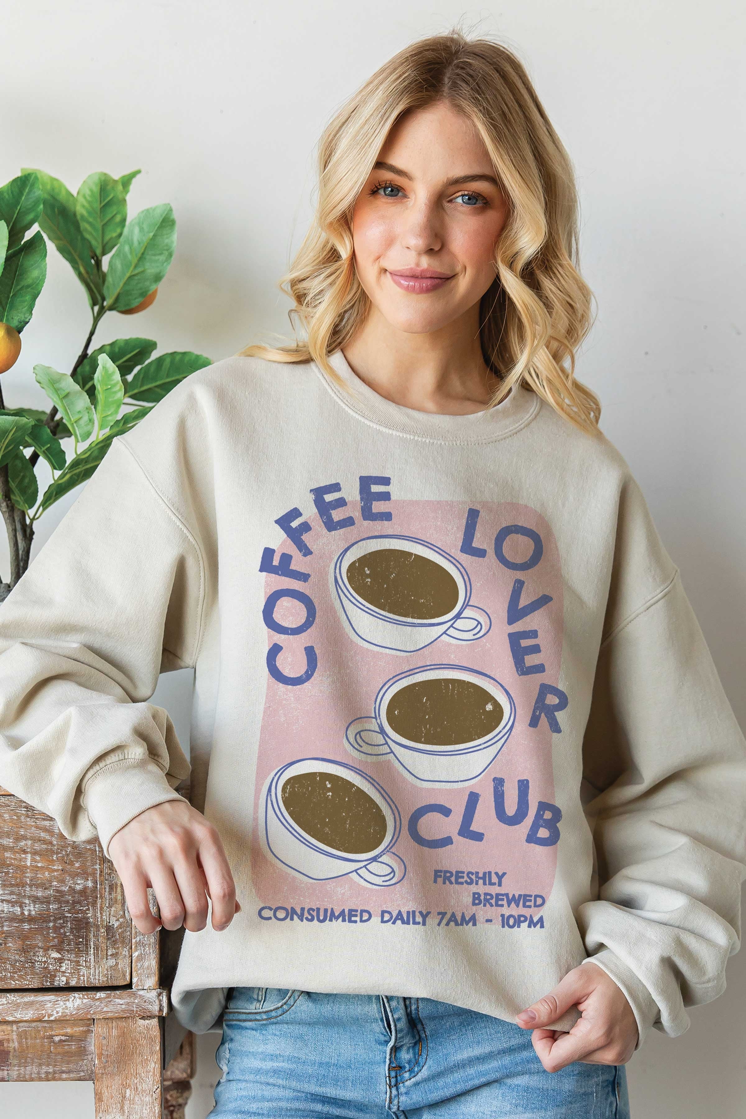 Woman wearing VacationGrabs coffee lovers club sweatshirt with coffee cup graphic and cozy fit
