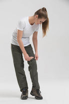 Woman adjusting VacationGrabs convertible pants for travel in olive green color, perfect for outdoor adventures