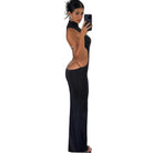 Woman wearing black backless cut out club dress taking a mirror selfie in a room with wooden floors