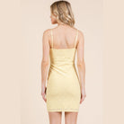Back view of a cute vacation mini dress in yellow with delicate eyelet pattern and adjustable straps
