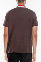 Back view of a man wearing a designer brown polo shirt by WEIV with red and beige collar details