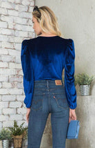 Elegant women's bodysuit in blue velvet with puffed sleeves, paired with denim for a stylish look
