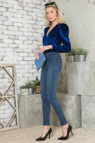 Elegant women's bodysuit in blue velvet with puff sleeves, styled with jeans and heels