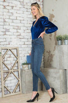 Elegant women's bodysuit in blue velvet with long puff sleeves paired with stylish jeans