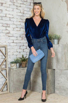 Elegant women's bodysuit in navy blue with puff sleeves, paired with skinny jeans and a clutch