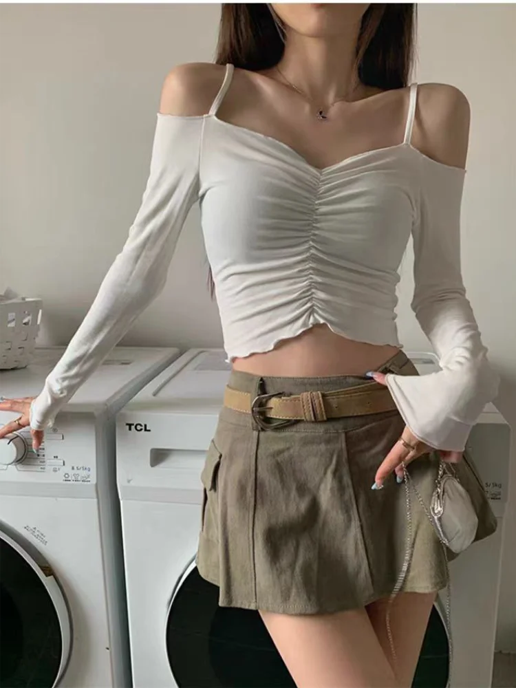 Woman wearing a white off shoulder crop top for women paired with an olive green skirt and beige belt