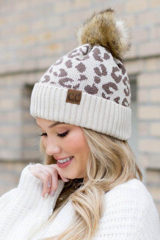 Fashionable animal print beanie with a faux fur pom pom, perfect for stylish winter wear.