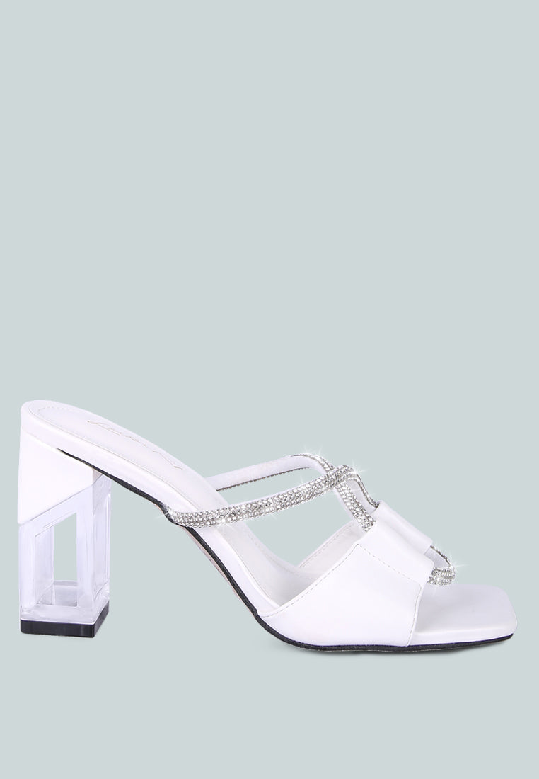 White sandal with a block heel and crystal embellishments on a light green background