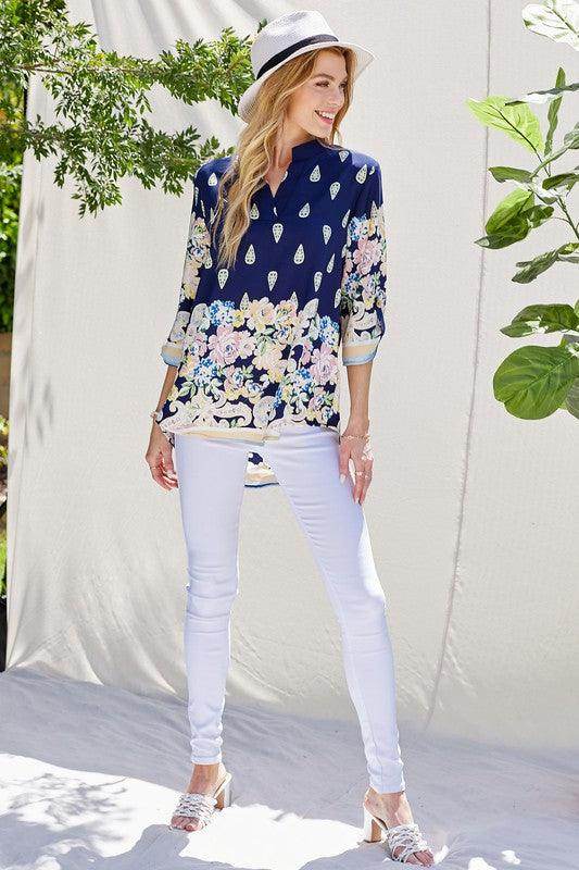Women's floral roll up sleeve top in navy with colorful floral design, paired with white skinny jeans