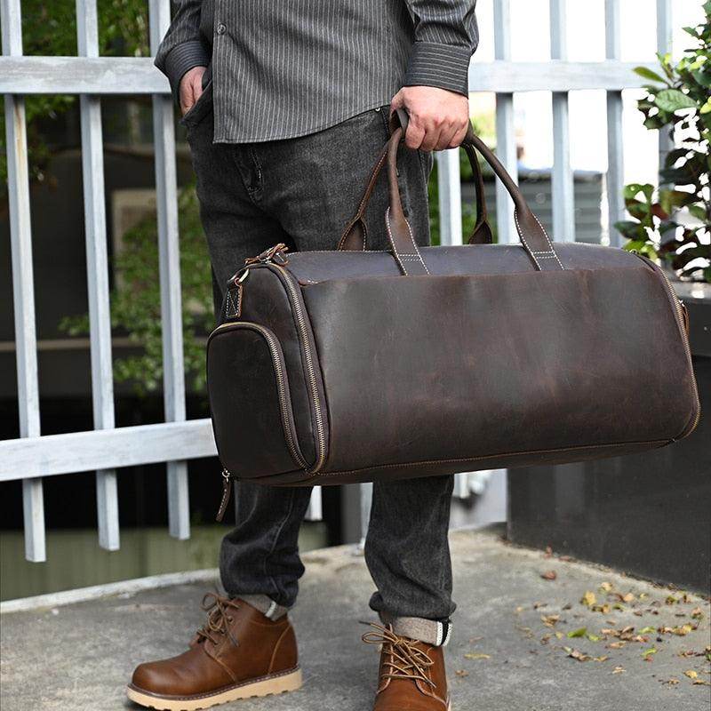Brown foldable leather suit bag held by a man, perfect for travel and stylish storage.