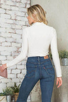 Chic women's form-fitting travel bodysuit in white, pairing beautifully with blue jeans