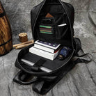 Interior of a genuine leather laptop backpack with books, a tablet, and organized pockets for accessories