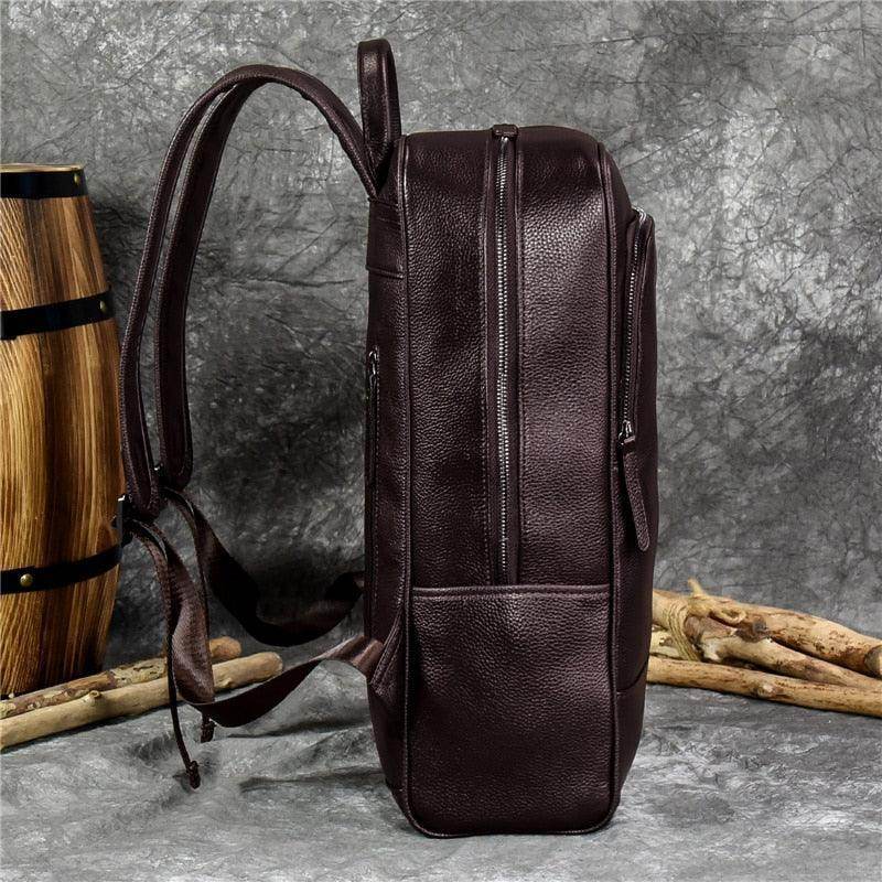 Side view of a genuine leather mens daypack in dark brown with multiple compartments and sturdy straps