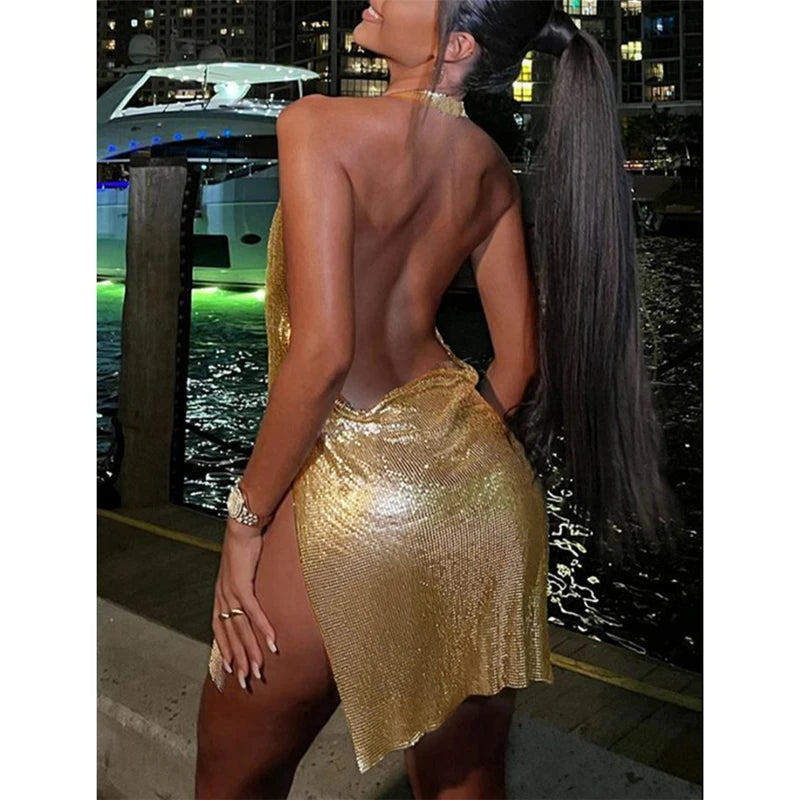 Woman wearing a shimmering gold glitter backless mini dress standing by waterfront at night