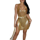 Woman wearing a gold glitter backless mini dress with halter neck and side slit holding a white purse