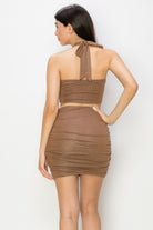Back view of woman wearing brown glitter tie top skirt set clubwear with halter neck and ruched skirt