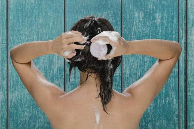Woman using BeNat handcrafted shampoo bar to lather her hair with natural ingredients