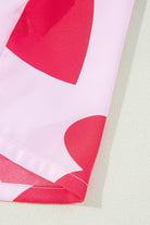 Close-up detail of YNIQUE heart print valentine pajamas set featuring red heart patterns on pink fabric