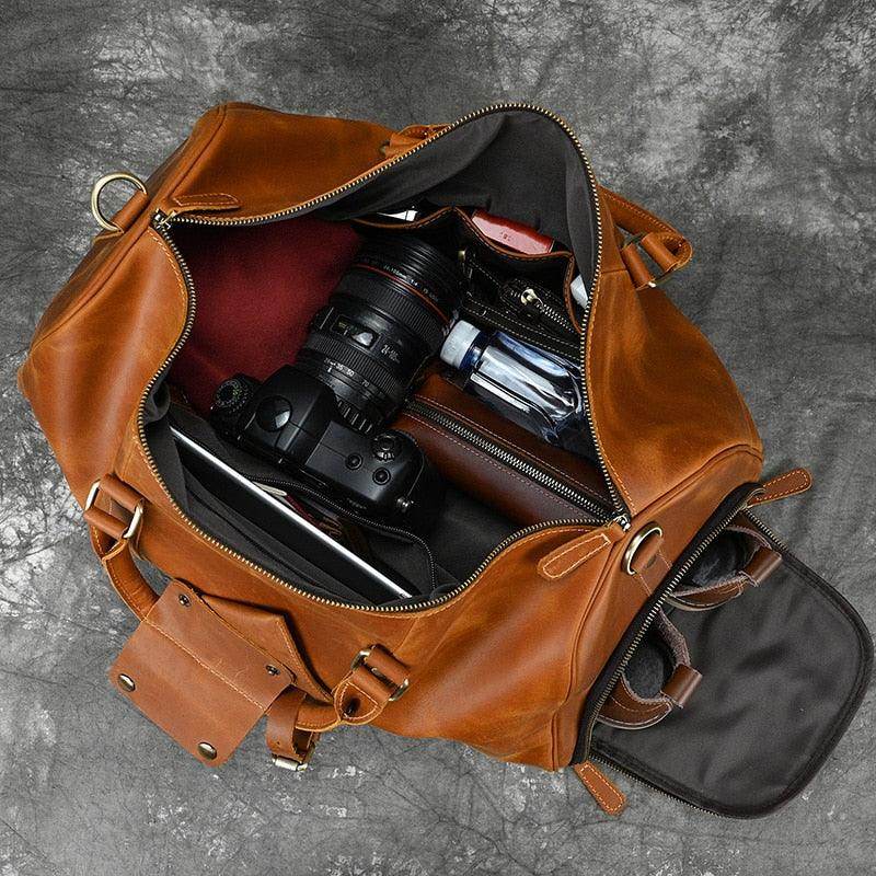 Top view of a hot leather carry-on bag filled with camera gear and travel essentials