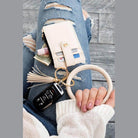 Aili's Corner ID holder keychain bracelet with wallet and keys attached, styled with ripped jeans