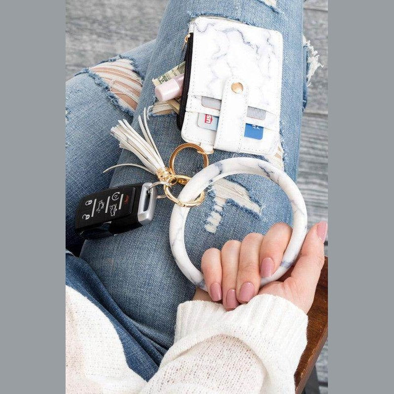 Elegant ID holder keychain bracelet in marble design, holding cards and a key fob on stylish denim.