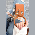 Aili's Corner ID holder keychain bracelet in brown with a wallet and car keys on a denim background
