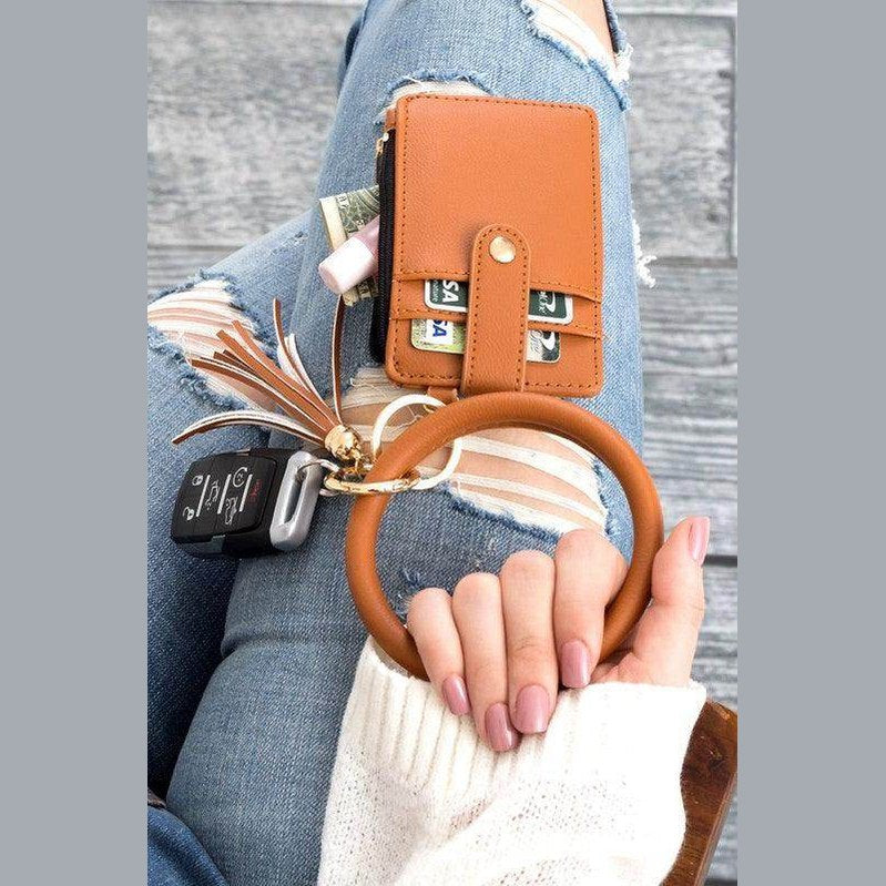 Aili's Corner ID holder keychain bracelet in brown with a wallet and car keys on a denim background