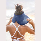 Stylish woman wearing a large brim bow beach hat enjoying the sunset at the beach