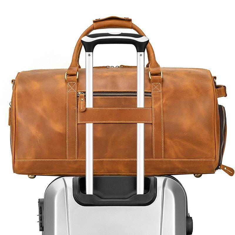 Large leather weekend bag in tan color, designed for travel and easy handling on luggage cart