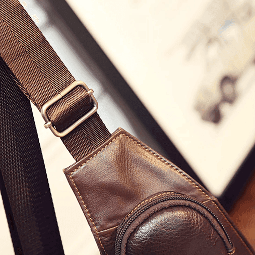 Detail of a leather sling bag for travel showcasing the adjustable strap and pocket design