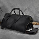 Black leather weekend bag with shoulder strap featuring spacious main compartment and separate shoe pocket