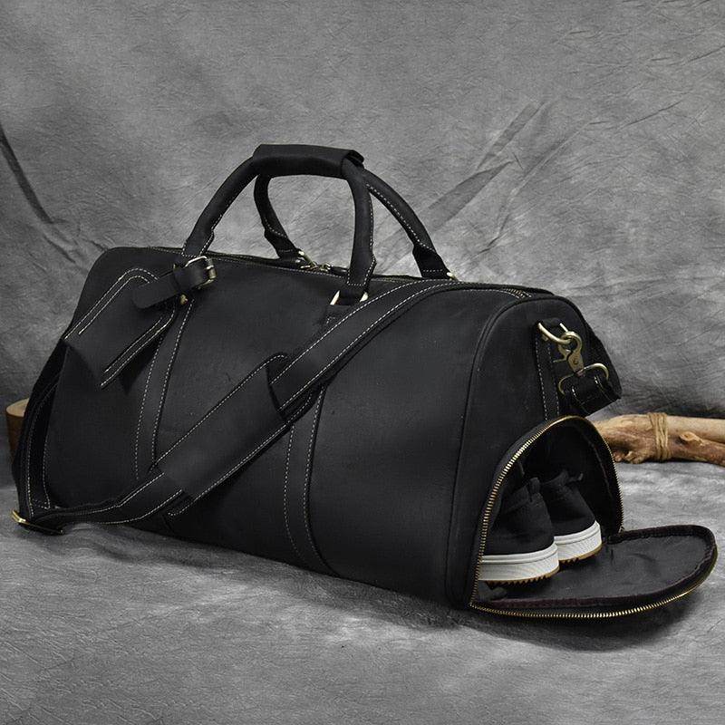 Black leather weekend bag with shoulder strap featuring spacious main compartment and separate shoe pocket