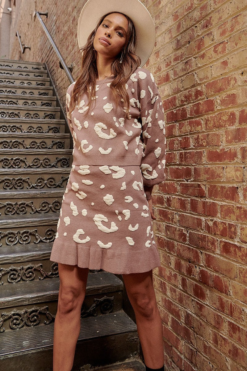 VacationGrabs leopard print mini skirt in beige with matching sweater worn by a woman near brick wall