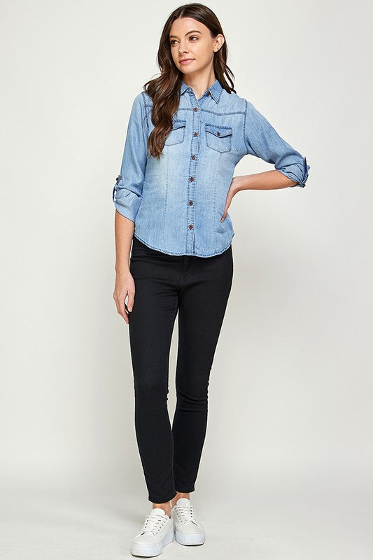 Blue Age lightweight denim shirt for travel worn by woman with rolled-up sleeves and black pants