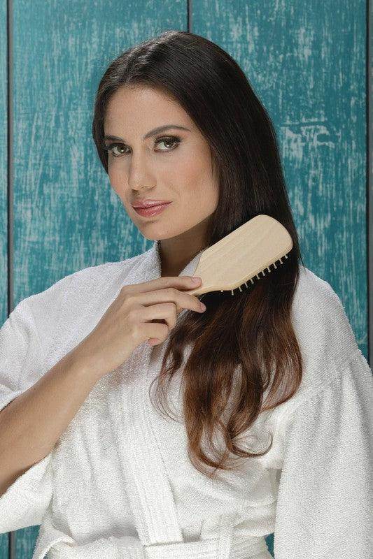 BeNat luxury bath essentials set featuring a model using a wooden hairbrush while dressed in a bathrobe