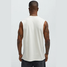 Back view of a mens graphic sleeveless shirt in white worn by a tattooed male model
